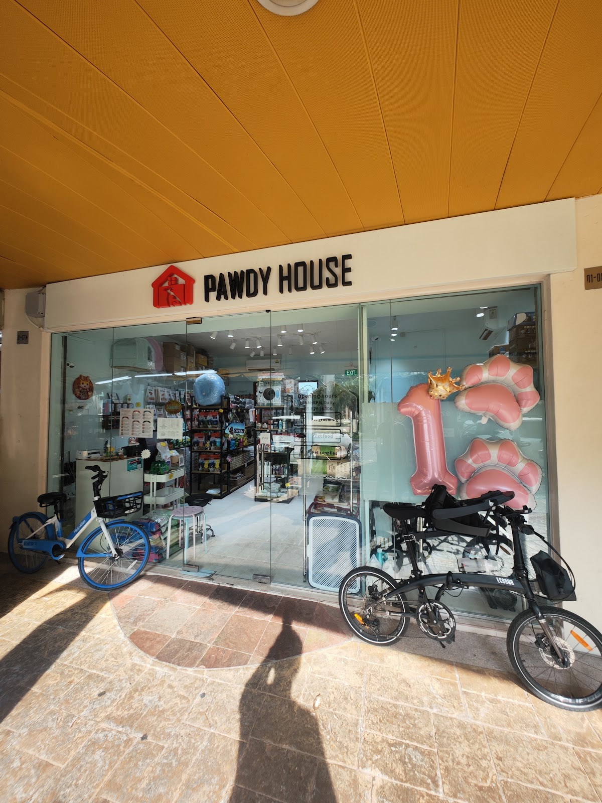 The Pawdy House shopfront with a pink number one balloon and paw balloons in the window